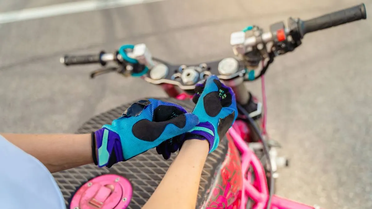 Paire de gants de moto ventilés posée sur un guidon, cuir perforé et maille technique