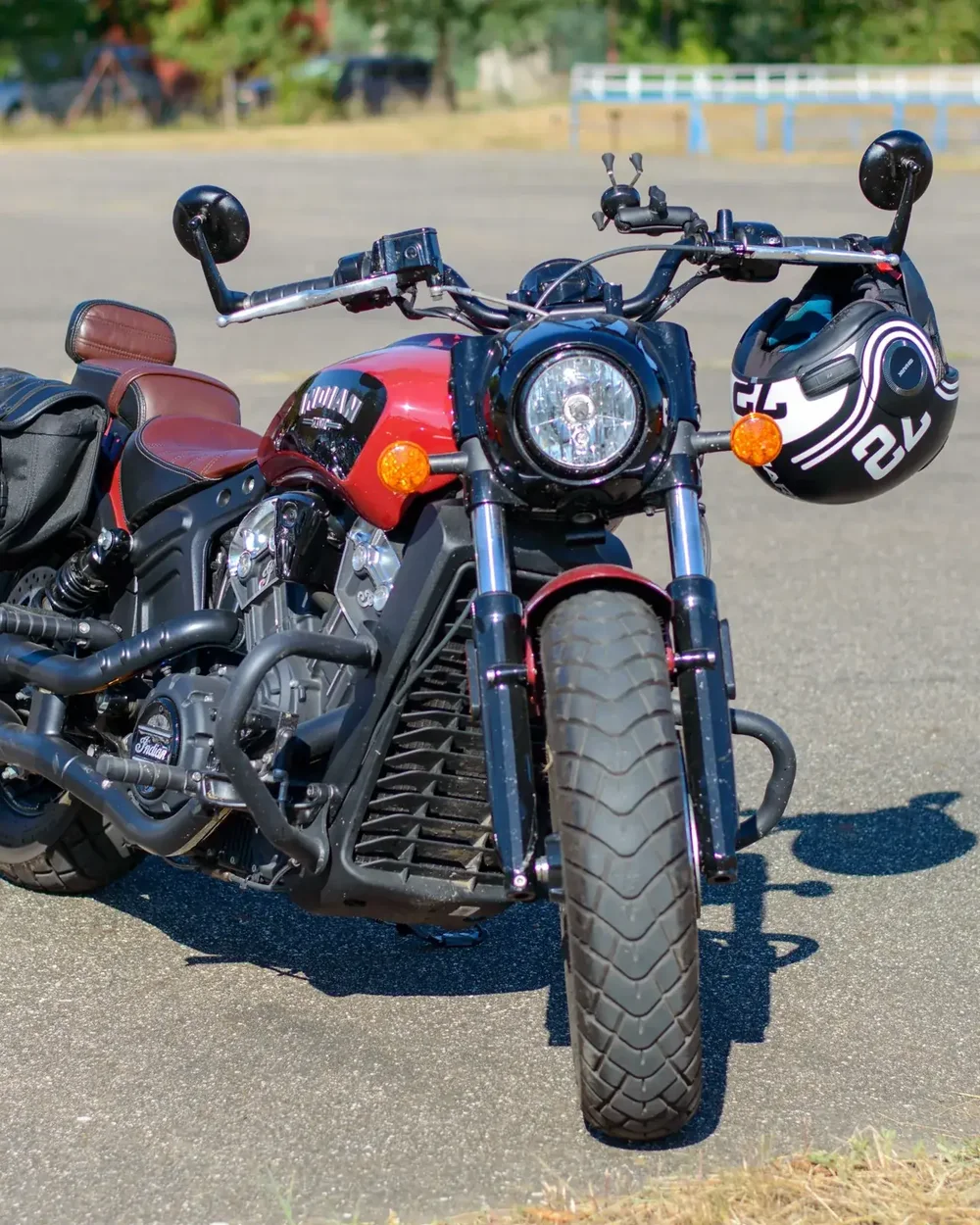Moto rouge garée en plein soleil, casque posé sur le guidon